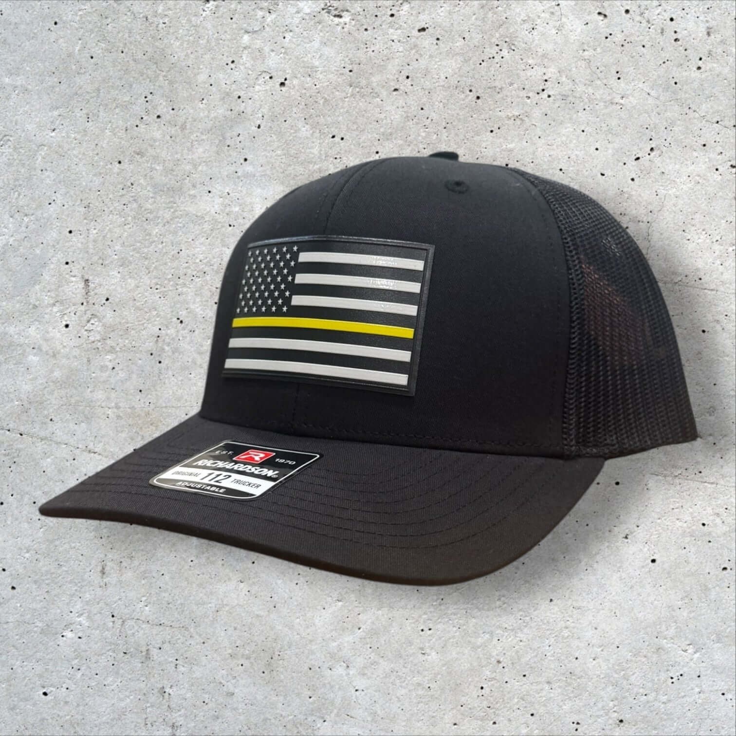 Thin Yellow Line Hat featuring a UV-printed American flag patch, durable black Richardson 112 trucker design.
